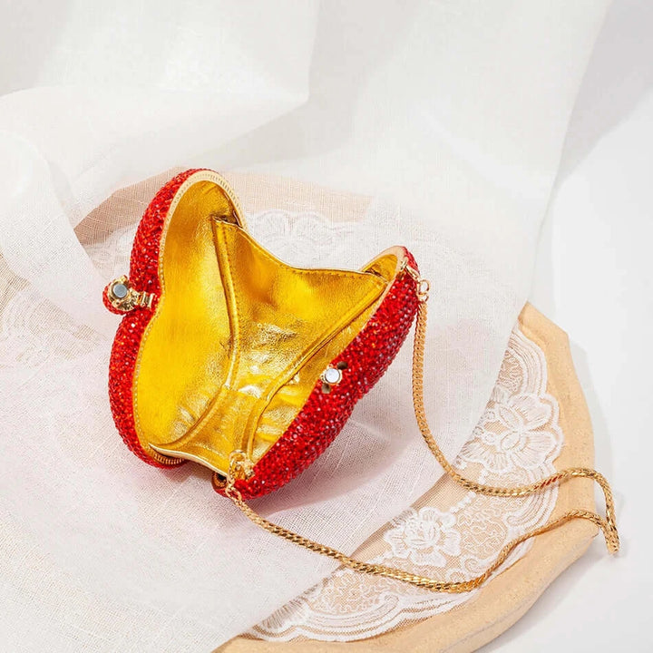 Inside view of a red heart-shaped rhinestone clutch bag with a golden interior and chain strap, perfect for sorority events.