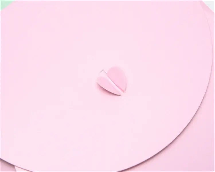 Close-up of a pink heart-shaped embellishment on a soft pink background, perfect for unique gift wrapping.