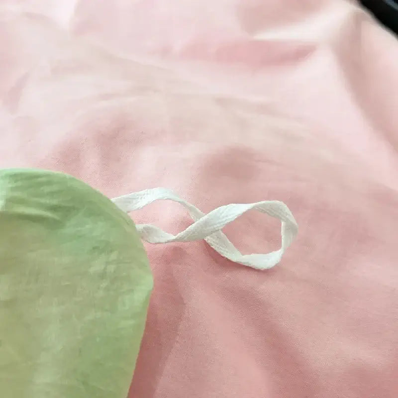 Close-up of pink and green fabric with a white ribbon, part of a luxurious Pink Green duvet bedding set.