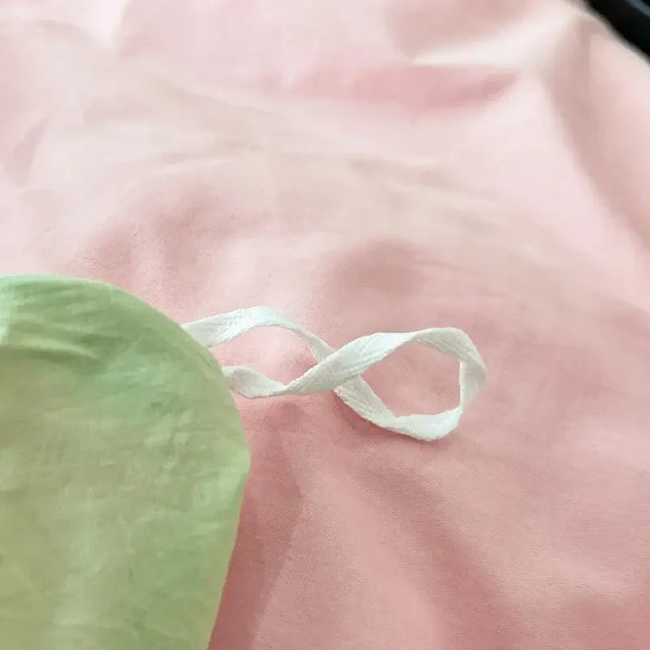 Close-up of pink and green fabric with a white ribbon, part of a luxurious Pink Green duvet bedding set.