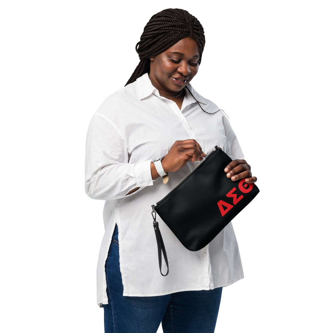 Woman wearing a white shirt, holding a Delta Sigma Theta Sorority crossbody bag with a bold logo, showcasing Greek gear style.