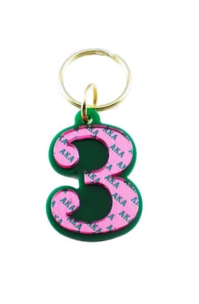 Pink acrylic number 3 keychain on green background, perfect for sorority and fraternity Greek gear paraphernalia.